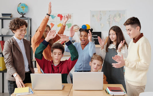 students and teachers looking at laptop